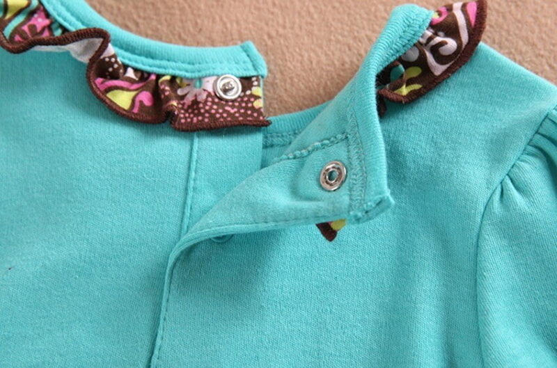 Close up of baby girl turquoise tunic with frill collar and popper fastening detail