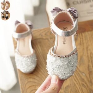 Girls silver crystal embellished party shoes with ankle strap and decorative bow shown in lifestyle setting