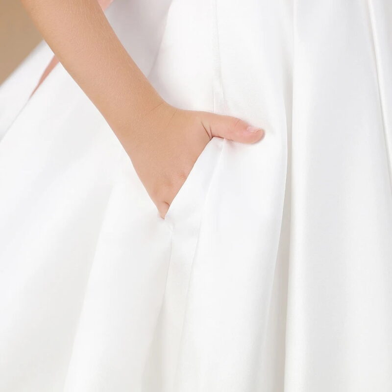 Close up of ivory flower girl dress showing hidden side pocket in the smooth satin skirt for added practicality