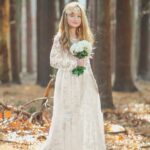 Girls Long Sleeve Lace Flower Girl Dress - ivory (10) Girl holding bouquet wearing ivory lace long sleeve flower girl dress in woodland setting