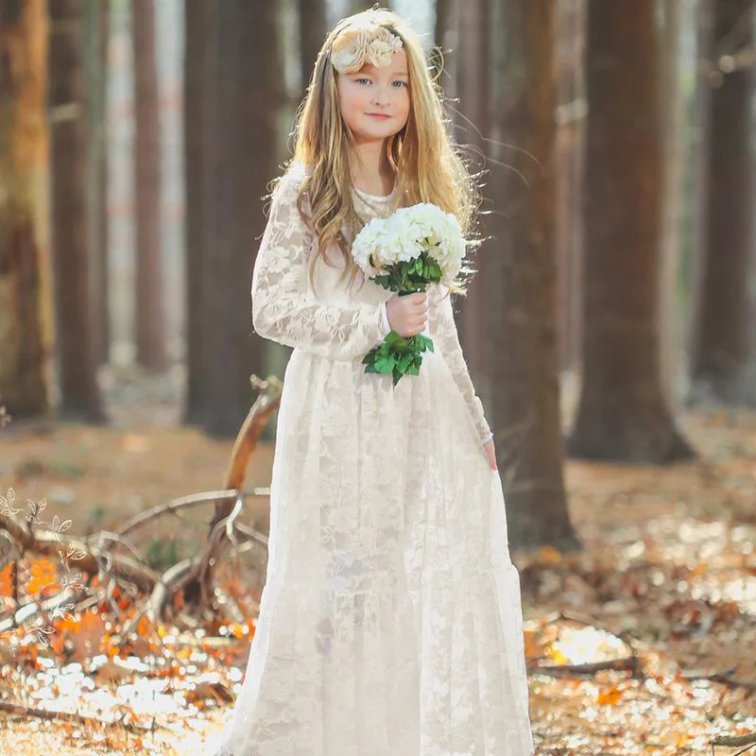 Girl holding bouquet wearing ivory lace long sleeve flower girl dress in woodland setting