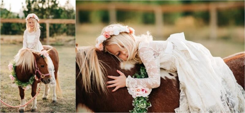 Girl in ivory lace flower girl dress sitting on pony outdoors with floral headband