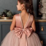 Back view of pink flower girl dress with pearl trimmed V back and oversized satin bow