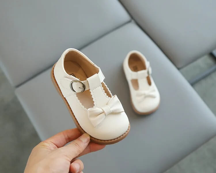 Off white girls T-Bar shoes with decorative bow, buckle strap and durable sole