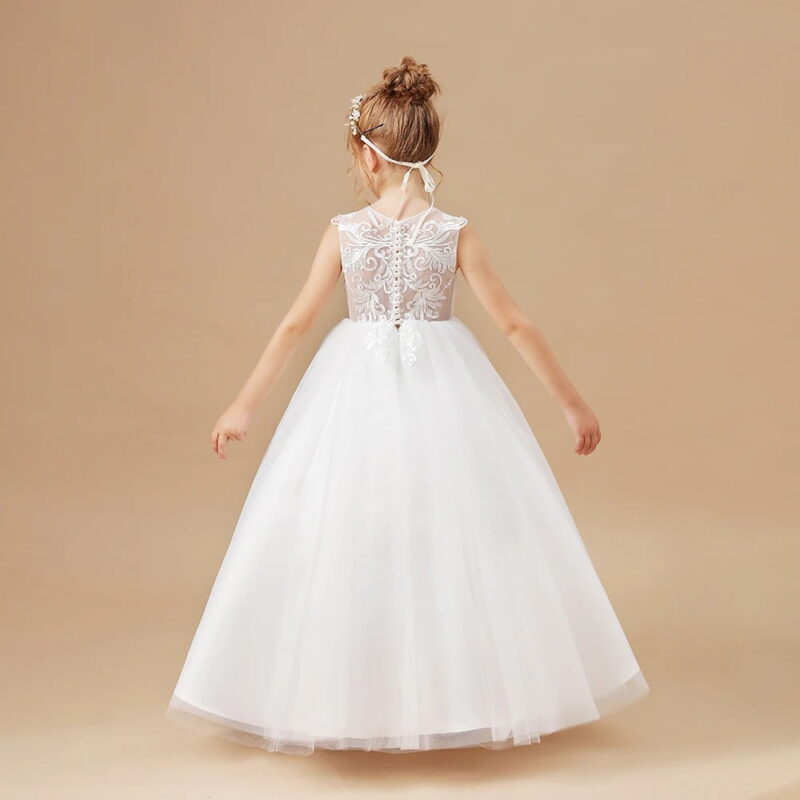 Back view of a girls white flower girl dress with illusion lace back, embroidered detailing, button fastening and layered tulle skirt