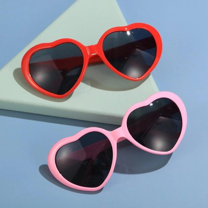 Heart shaped diffraction glasses in red and pink with dark lenses, novelty sunglasses creating heart light effects for festivals and parties
