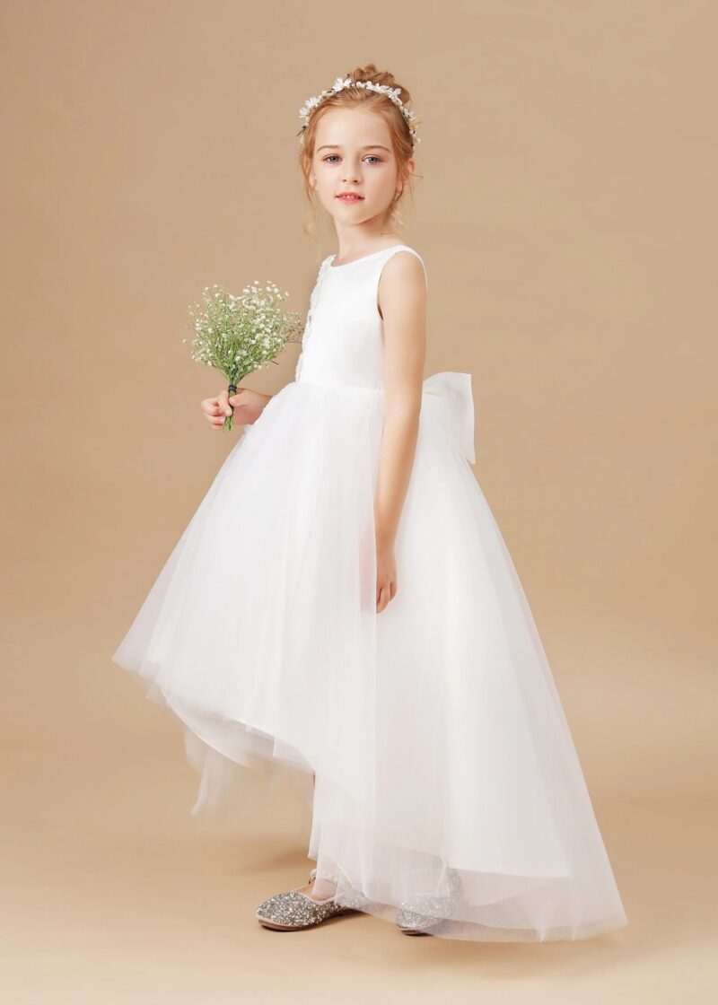 Side view of girls white high low flower girl dress with flowing tulle skirt and floral detail, classic wedding outfit