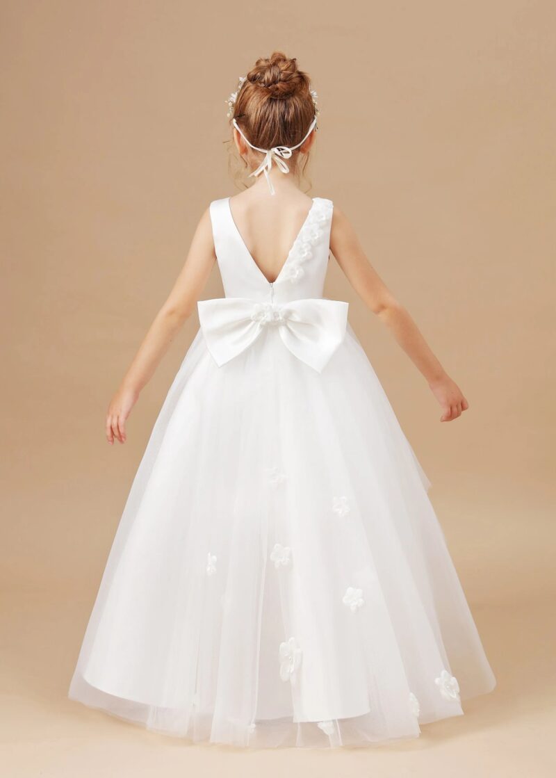 Back view of girls white high low flower girl dress with bow detail, tulle skirt and floral accents