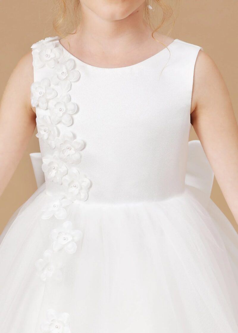 Close up of girls white flower girl dress bodice with 3D floral appliqué and pearl detail, delicate wedding dress design