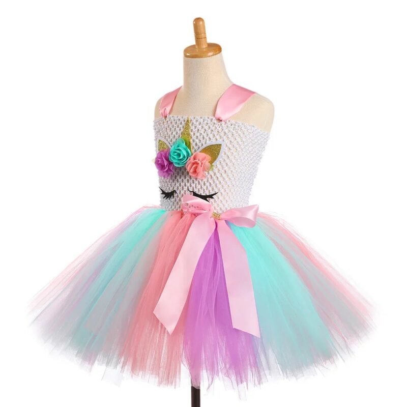Angled view of Rainbow Wonderland Unicorn Tutu Dress Set with pastel rainbow tulle skirt, unicorn face design, floral embellishments and pink satin waist bow
