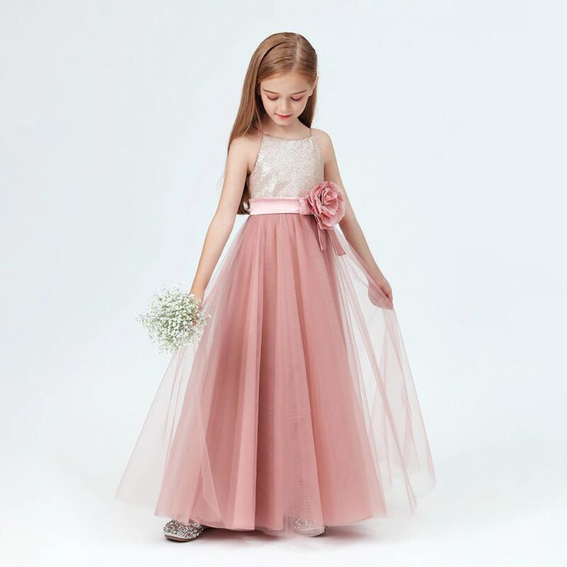 Young girl wearing dusty pink sequin junior bridesmaid dress with floor length tulle skirt and floral waist detail.
