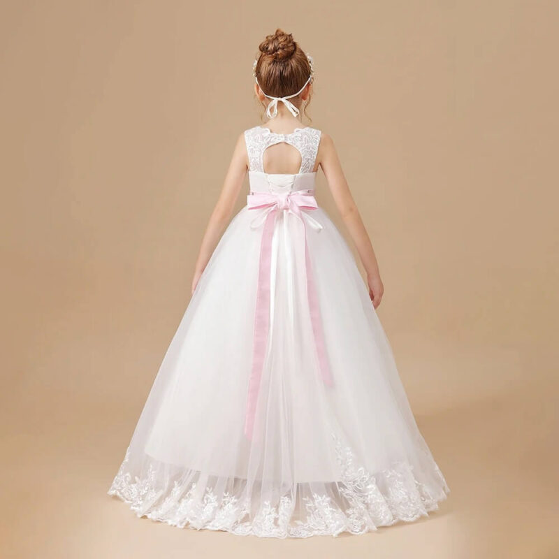 Back view of white flower girl gown with pink satin bow, flowing tulle skirt and embroidered lace hem.