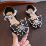 black Girls Sparkly Butterfly Bow Shoes (1) Girls black sparkly shoes with butterfly bow embellishment and pearl ankle strap for formal events