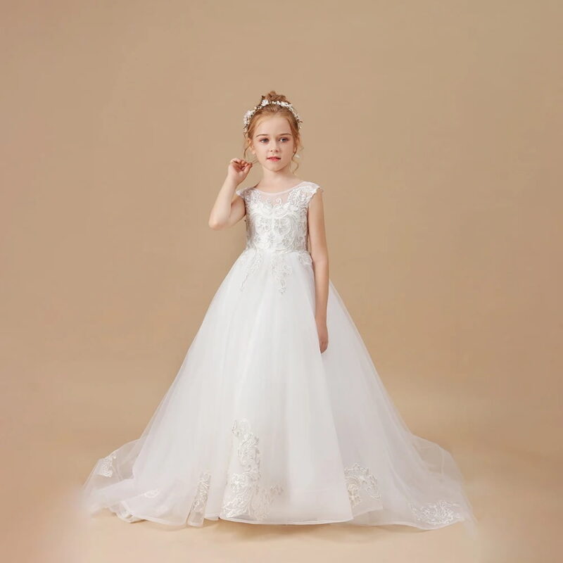 Young flower girl wearing an ivory lace train ball gown with flowing tulle skirt and delicate floral embroidery.