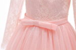 Close up front detail of pink flower girl dress with lace bodice, satin bow waistband and tulle skirt