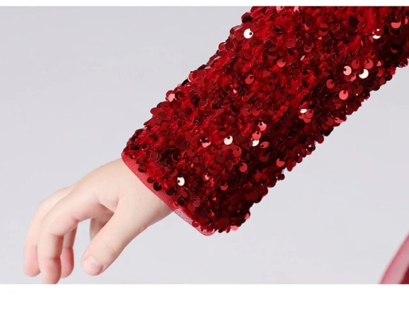 Close up of the long sleeve covered in shimmering red sequins on the girls formal occasion dress