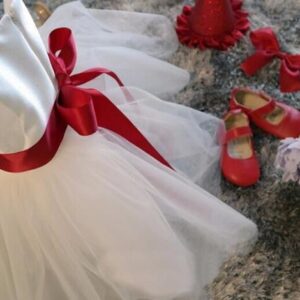 Side view of white flower girl dress featuring red satin waist sash, large ribbon bow and soft layered tulle skirt for formal events.