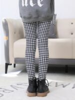 Back view of girl wearing black and white houndstooth print winter leggings with black ankle boots.