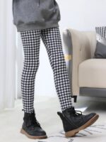 Girl modelling black and white houndstooth print winter leggings with a grey sweatshirt and black ankle boots.