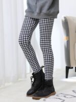 Black and white houndstooth print winter leggings for girls styled with a grey sweatshirt and black lace-up boots.