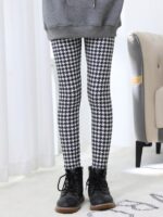 Front view of girl wearing black and white houndstooth print winter leggings with black ankle boots.