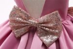 Close-up of pink princess party dress for girls with large sparkling sequin bow at the waist