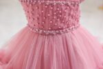 Close-up of pearl embellished dark pink bodice and decorative floral trim on girls tulle occasion dress