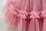 Close-up of dark pink ruffled tulle skirt with gathered floral trim on girls princess occasion dress