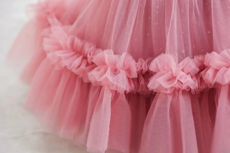 Close-up of dark pink ruffled tulle skirt with gathered floral trim on girls princess occasion dress