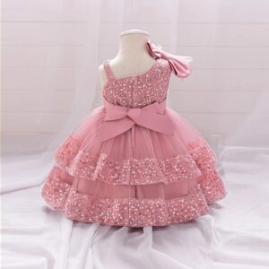 Back view of pink one shoulder sequin tulle gown for toddler girls with large bow and layered skirt