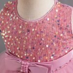 Close-up of pink sequin bodice on girls party dress with satin waist bow and pearl embellishment