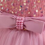 Close-up of pink satin waist bow with pearl embellishment on girls sequin and tulle party dress
