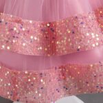 Close-up of sparkling pink sequin trim on layered tulle skirt of girls party dress