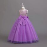 Side view of purple girls occasion ball gown with gold sequin bodice, satin bow and sparkling full tulle skirt