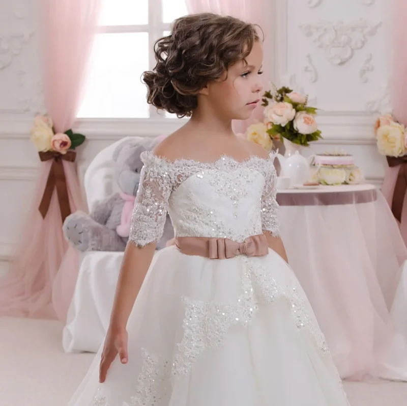 Close up of ivory off shoulder sequin lace flower girl dress with detailed bodice and satin waist