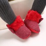 Baby wearing ribbed knit Christmas boots with faux fur trim and non slip soles