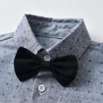 Close up of black bow tie on boys grey patterned formal shirt