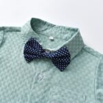 Close up of navy polka dot bow tie on sage green textured boys shirt