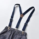 Close up of adjustable navy suspenders on grey boys formal trousers