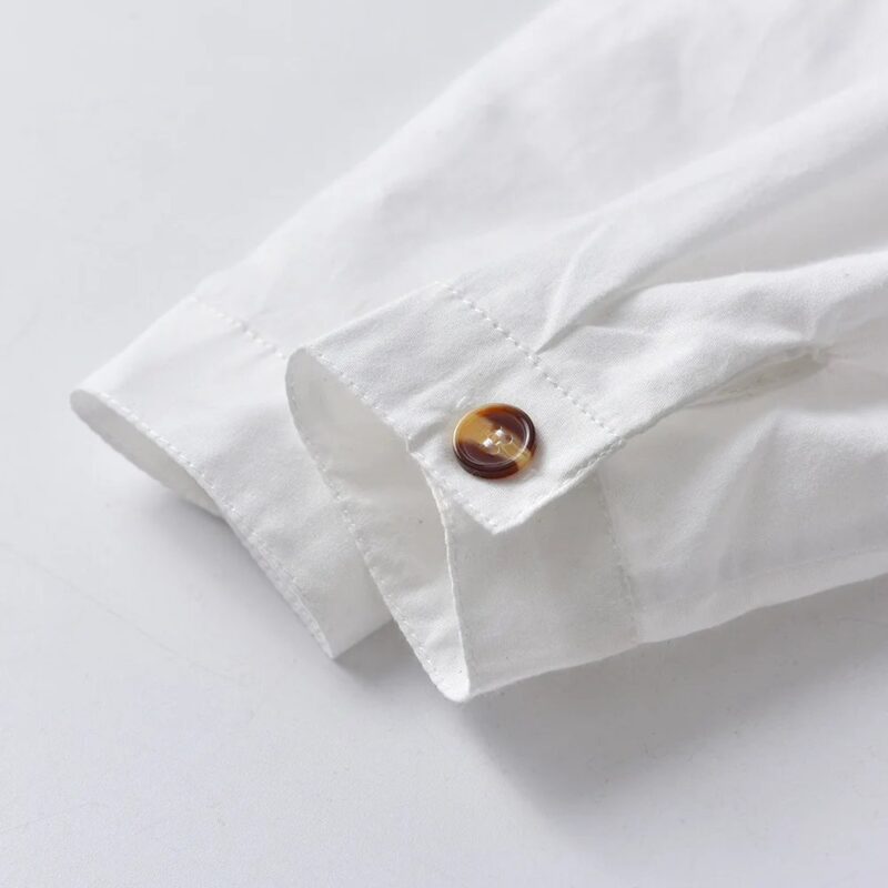 Close up of boys white shirt cuff with decorative button fastening