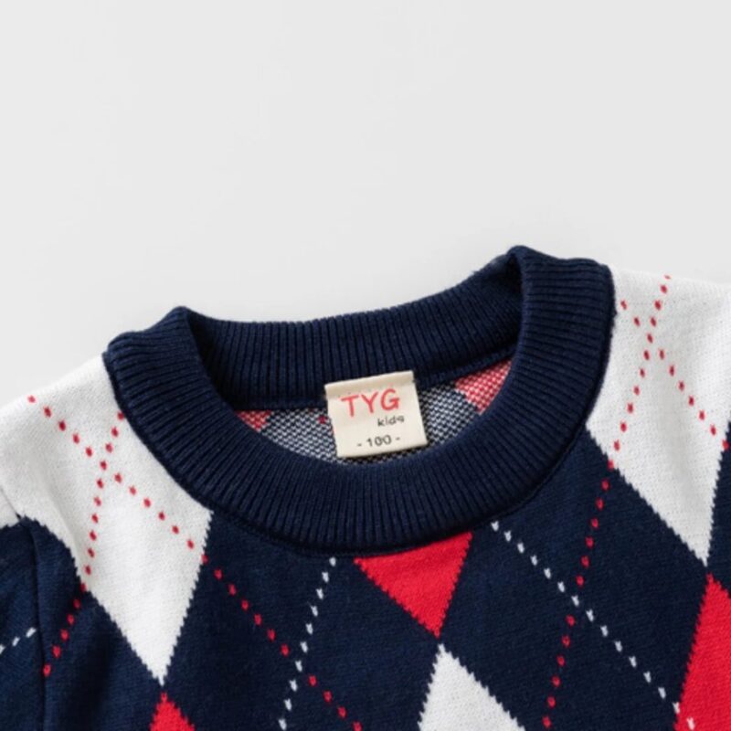 Close-up of kids argyle knit jumper showing navy ribbed crew neck and red, white and navy diamond pattern.