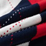 Kids Argyle Knit Jumper - red multi (6) Close-up of soft knitted fabric on kids argyle jumper showing navy, red and white diamond pattern and fine stitch detail.