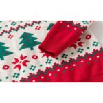 Close-up of kids cream Christmas jumper showing red ribbed sleeve cuff, green Christmas trees and festive knitted pattern.