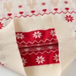 Inside view of kids cream Fair Isle Christmas jumper showing festive red knitted pattern and ribbed cream hem.