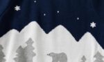 Close-up of kids Christmas jumper showing grey polar bear, pine trees, snowy mountains and white snowflakes on navy.