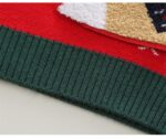 Close-up of dark green ribbed hem on red kids reindeer Christmas jumper showing the textured knitted finish.