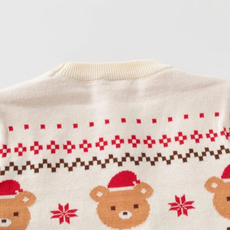 Close-up back view of kids cream Christmas jumper showing Santa bear faces, red snowflakes and Fair Isle knitted pattern.