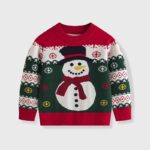 Kids Snowman Christmas Jumper (1) Kids Christmas jumper in red, green and white with a large snowman, festive snowflakes, scarf and traditional knitted patterns.